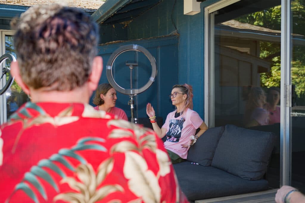 Four people recording an outdoor video interview on a deck using ring lights and a laptop at Infinite Tree.