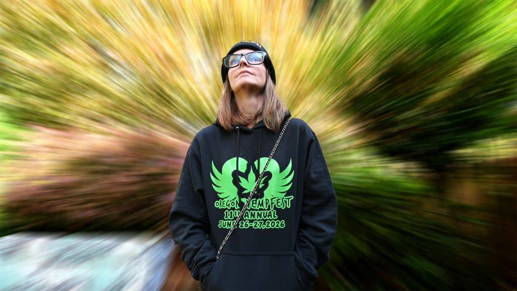 Vegi Hoyt wearing an Oregon Hempfest 2026 hoodie looking up against a dynamic motion blur nature background.